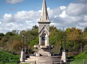 A stone monument with pointed spire at the side of road.
