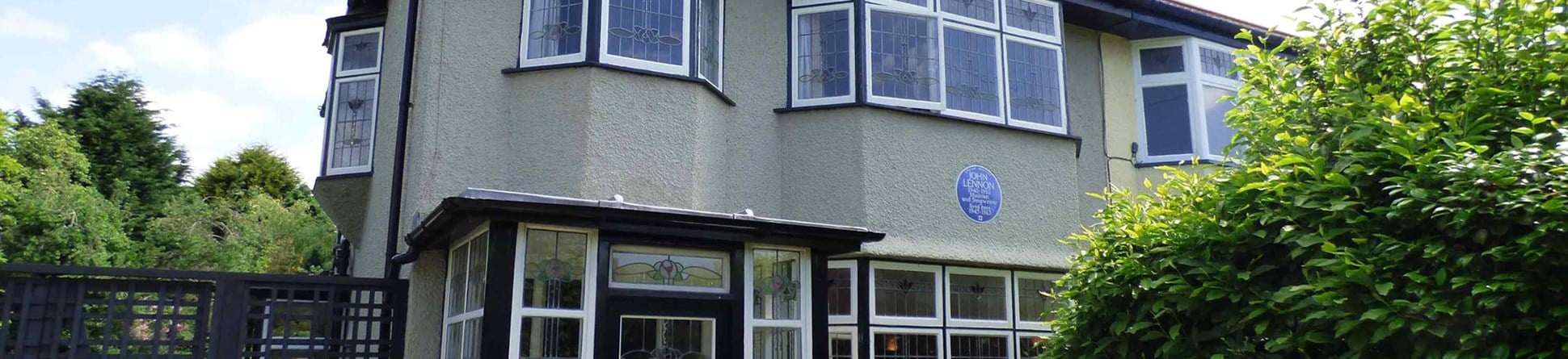 The front exterior of a semi-detached house in Liverpool with a Blue Plaque celebrating the singer, songwriter, musician and peace activist John Lennon