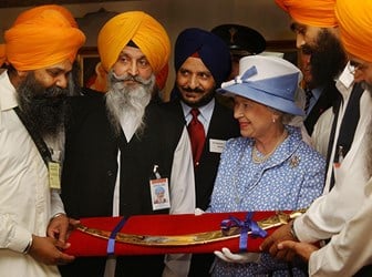 Queen Elizabeth II receives a ceremonial sword (tulwar) as a gift, at the end of a visit to the Sikh Gurdhwara Temple in Leicester. 1 August 2002 © PA Images / Alamy Stock Photo