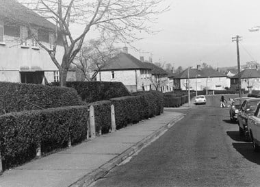 Black and white photo of a quiet street in a council housing estate.