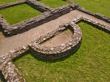 A semi-circular structure abuts the stone foundations of an archaeological remains. 