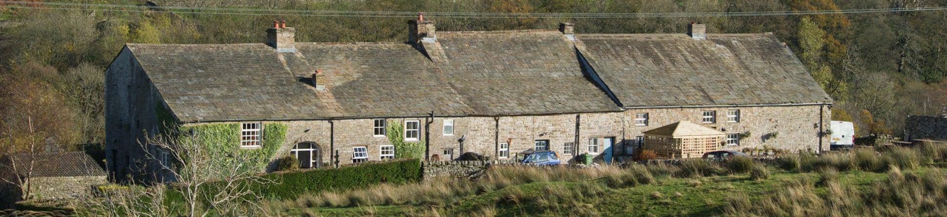 A row of stone cottages with moorland in the foreground and background.