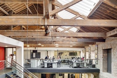 An interior photograph of a first-floor office space underneath a roof with exposed wooden beams and skylight windows.