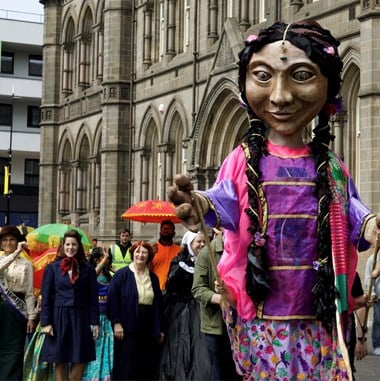 A large street carnival puppet and surrounding crowd in front of a civic building in Middlesborough.