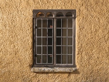 Wood and lead framed window set in a rendered wall.