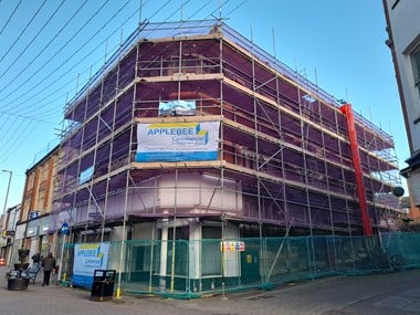 Three-storey corner building shrouded in scaffolding.