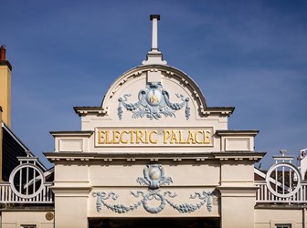 The facade at the top of the exterior entrance to the Electric Palace Cinema shows scrolling decoration and the words 1911 and Electric Palace within an arched top section of the facade.