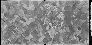 A black and white vertical aerial photograph of an airfield with three runways set within a landscape formed of a patchwork of fields.