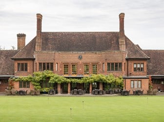 General exterior view of a golf clubhouse, with a practice putting green in the foreground