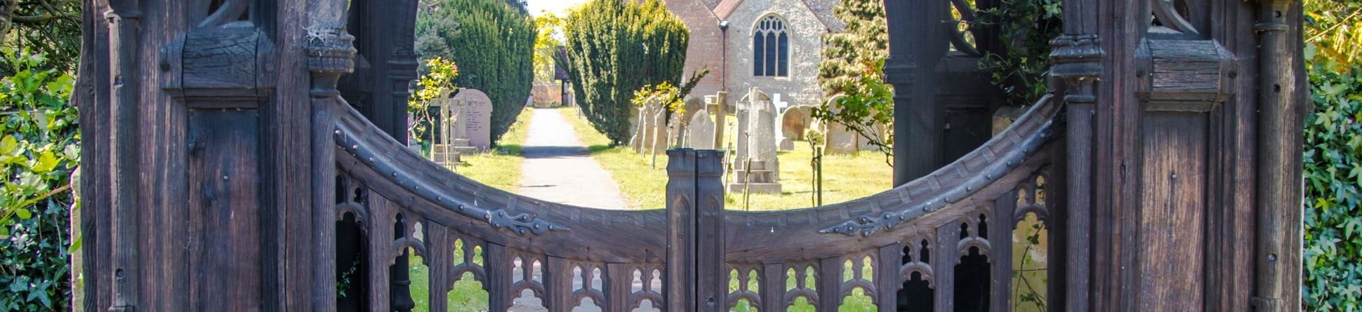 Decorative carved wooden gateway leading towards a church.