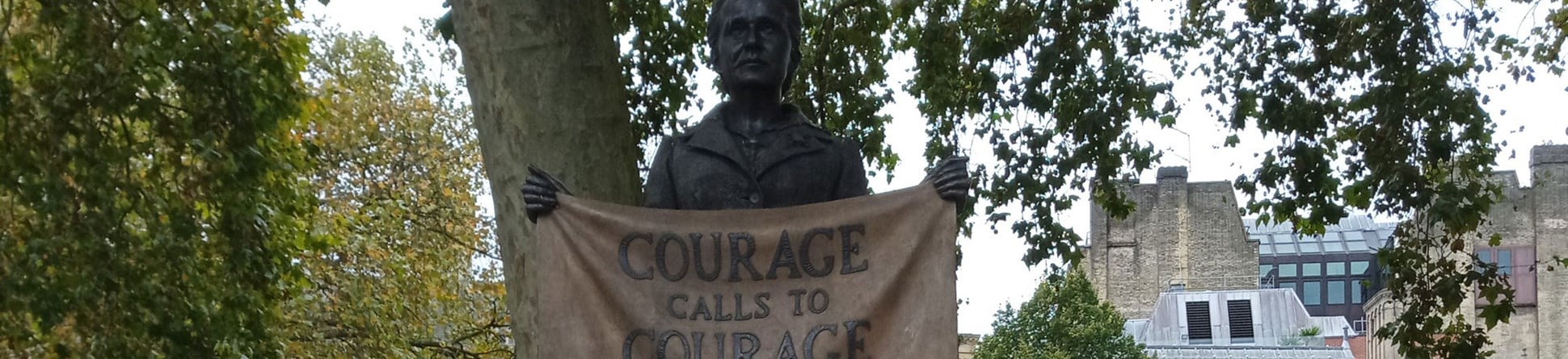 A bronze statue of a woman in Edwardian clothing holding a banner in front of her which reads 'courage calls to courage everywhere'. On the plinth are small portraits of other women.