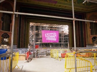 Interior view of a theatre with scaffolding and a large pink banner reading Soho Theatre Walthamstow.