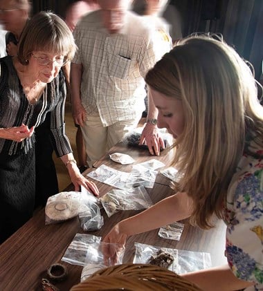 People examining artefacts in plastics bags on a table