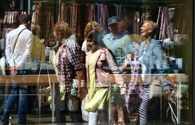 People walking in a street reflected in a shop window