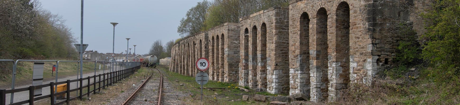 A series of stone arches next to a railway line. 