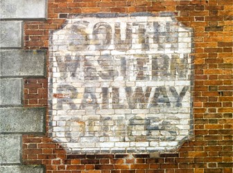 A close-up of a painted sign on a red brick wall.
