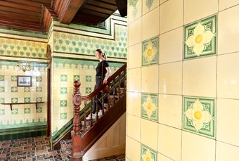 Staff member descends a staircase, flanked by yellow tiled walls.