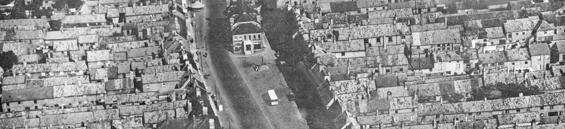 A black and white archive aerial view of a High Street.