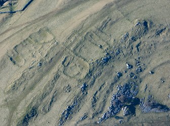 A colour aerial view of earthworks in a rocky moorland landscape.