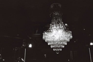 A chandelier glows with light, the rest of the photo appears dark 