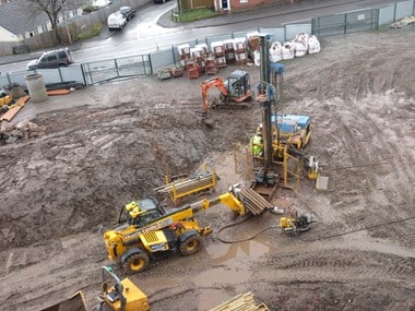 Yellow heavy plant machines on a muddy site.