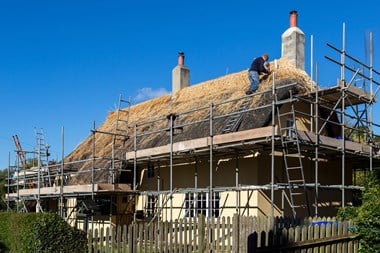 Ridge thatching on a house with scaffolding.