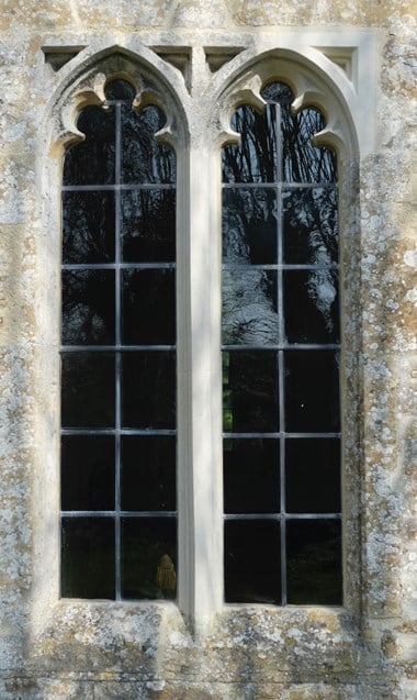 Newly restored church window from the outside of the church. The windows are surrounded by grey stone masonry. 