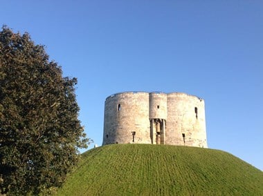 A castle tower on a hill against a backdrop of clear blue sky 