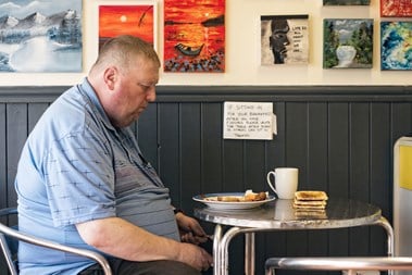Portrait of a man eating breakfast at a cafe.